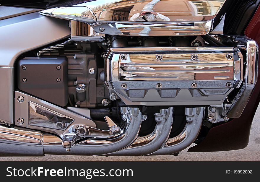 A closeup detailed view of chrome exhaust pipes and engine components on a big chopper bike. A closeup detailed view of chrome exhaust pipes and engine components on a big chopper bike.