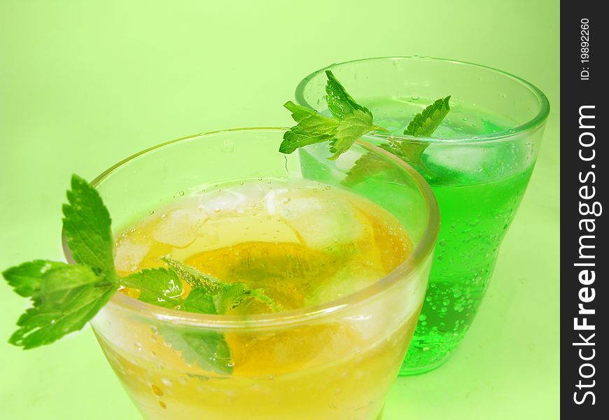 Two glasses of fruit green and yellow lemonade with ice and mint