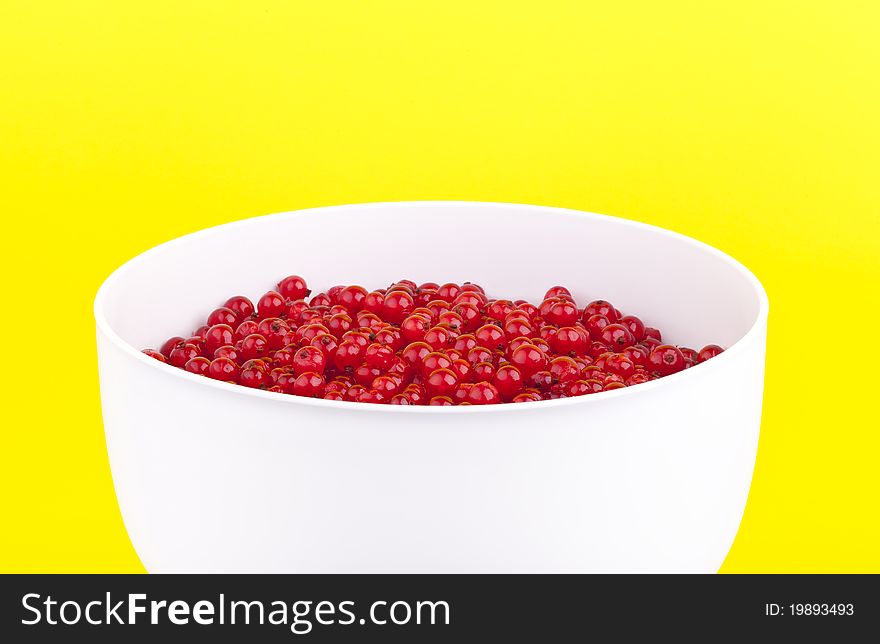 Studio-shot of a bowl with fresh redcurrants, on a yellow background.