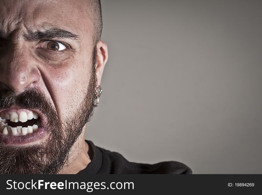 Mid-frontal portrait of a man yelling on grey background