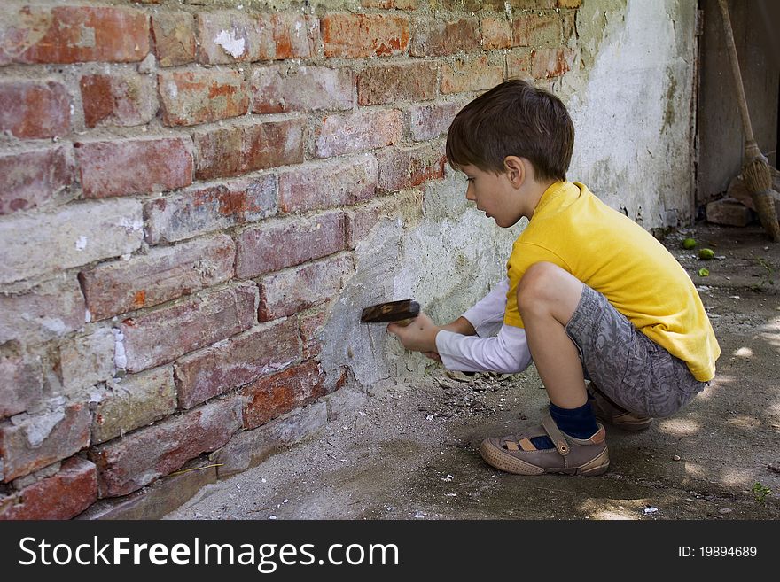 Young boy wreck an old brick wall with a hammer. Young boy wreck an old brick wall with a hammer