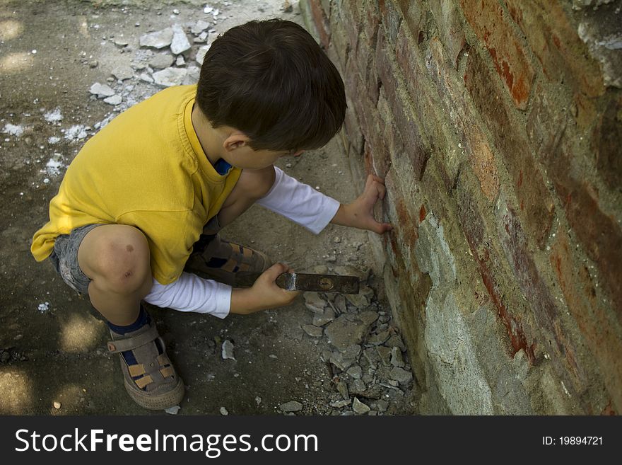 Young boy wreck an old brick wall with a hammer. Young boy wreck an old brick wall with a hammer