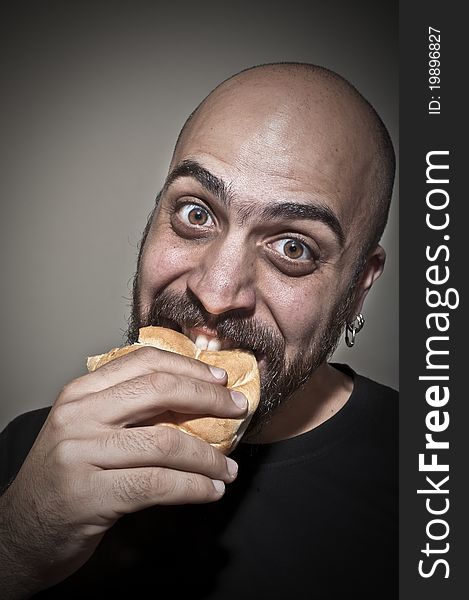 Happy man eating a sandwich on dark background