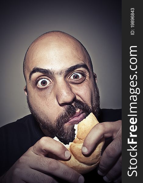 Funny man eating a sandwich on dark background