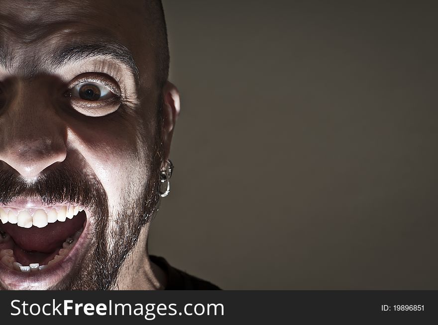 Mid-frontal portrait of a man yelling on grey background