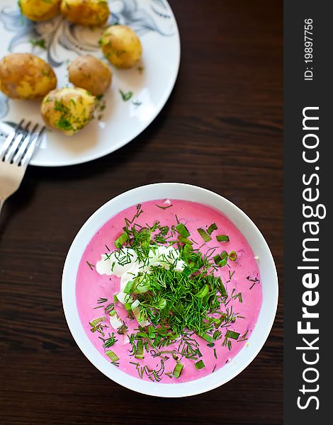 Traditional lithuanian cold borscht with beet and eggs, served with young hot potatoes