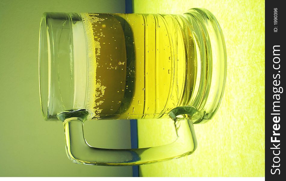 A glowing mug of beer on illuminated glass. A glowing mug of beer on illuminated glass