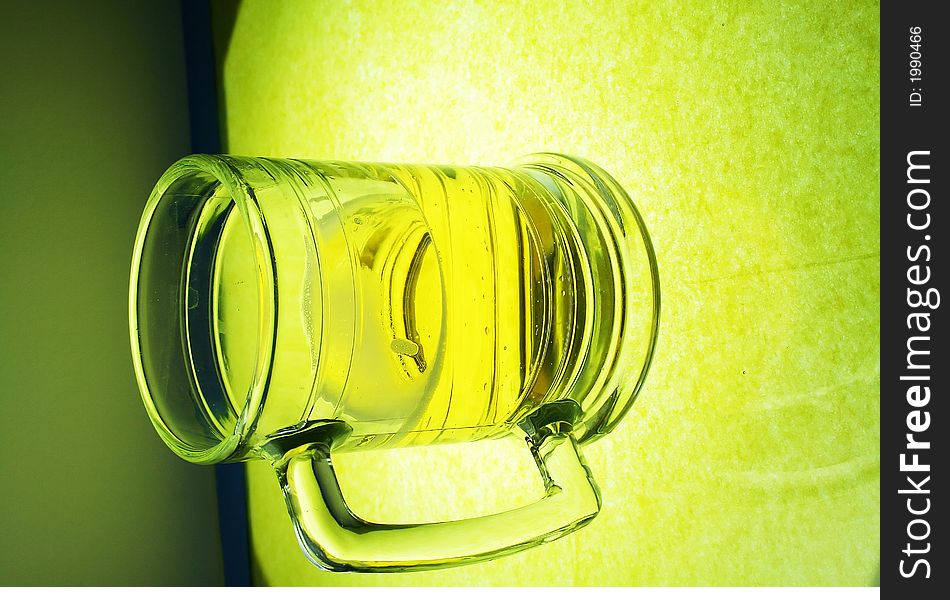 A glowing mug of beer on illuminated glass. A glowing mug of beer on illuminated glass