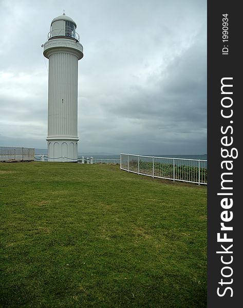 White lighthouse, dark grey sky, almost raining, coastline near sydney