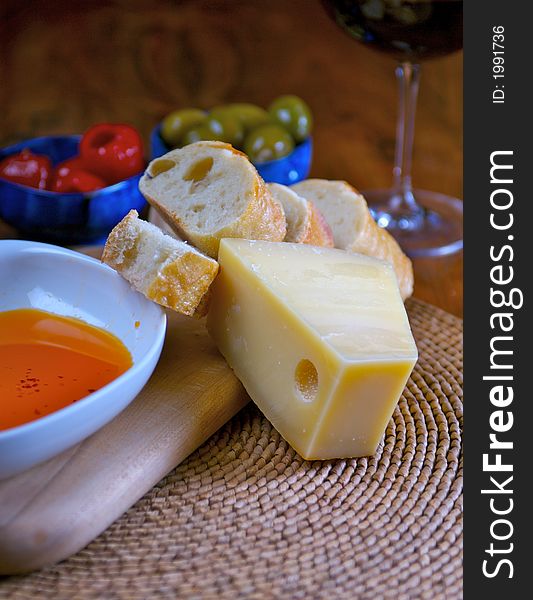 Wine, cheese, bread, olives, pepper and dipping oil read for a snack. Wine, cheese, bread, olives, pepper and dipping oil read for a snack