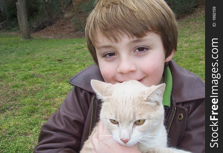 Close up of young boy and pet cat in field. Close up of young boy and pet cat in field