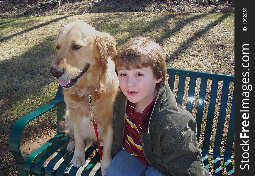 Boy and golden retriever on bench