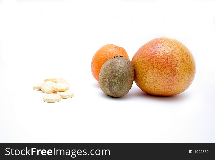 Fresh fruits versus pills, on white surface