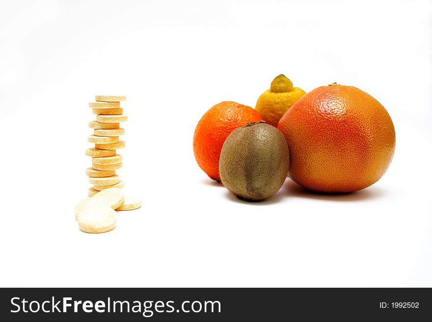Fresh fruits versus pills, on white surface
