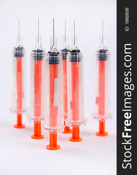 Six standing syringes on white background