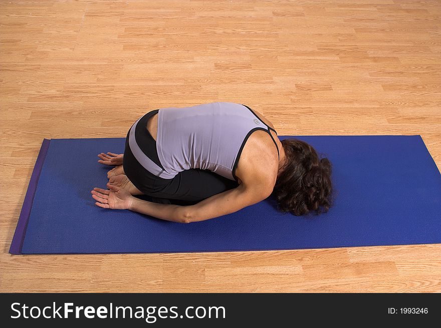 Woman doing yoga on blue mat in studio