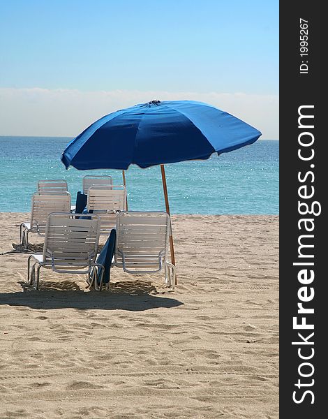 Several beach chairs and blue beach umbrella. Several beach chairs and blue beach umbrella