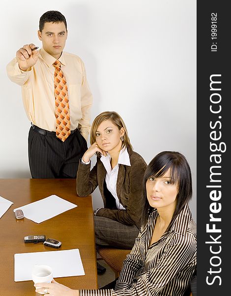 Two women and a man are at the table. Man's standing and pointing screen (camera). Two women and a man are at the table. Man's standing and pointing screen (camera).