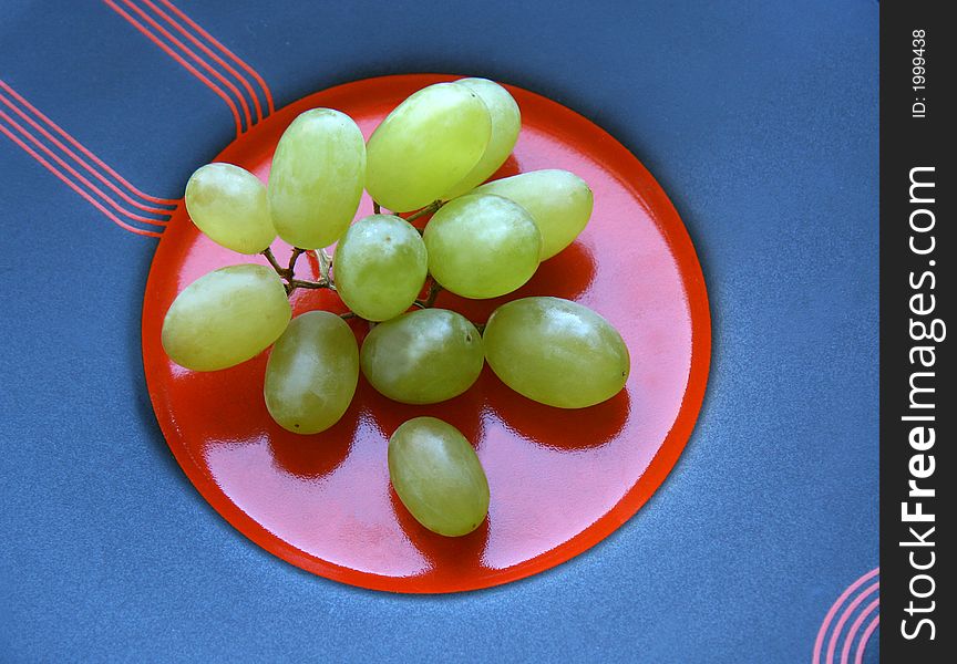 The cluster of grapes laying on a dark plate with red circle in the center. The cluster of grapes laying on a dark plate with red circle in the center.
