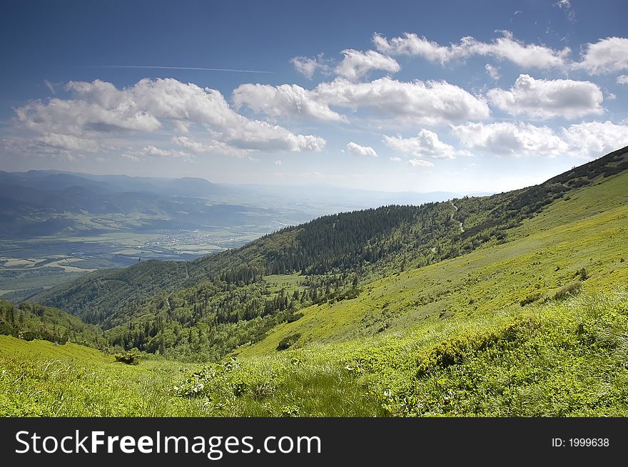 Mountain landscape - green filed, the blue sky and white clouds. Mountain landscape - green filed, the blue sky and white clouds