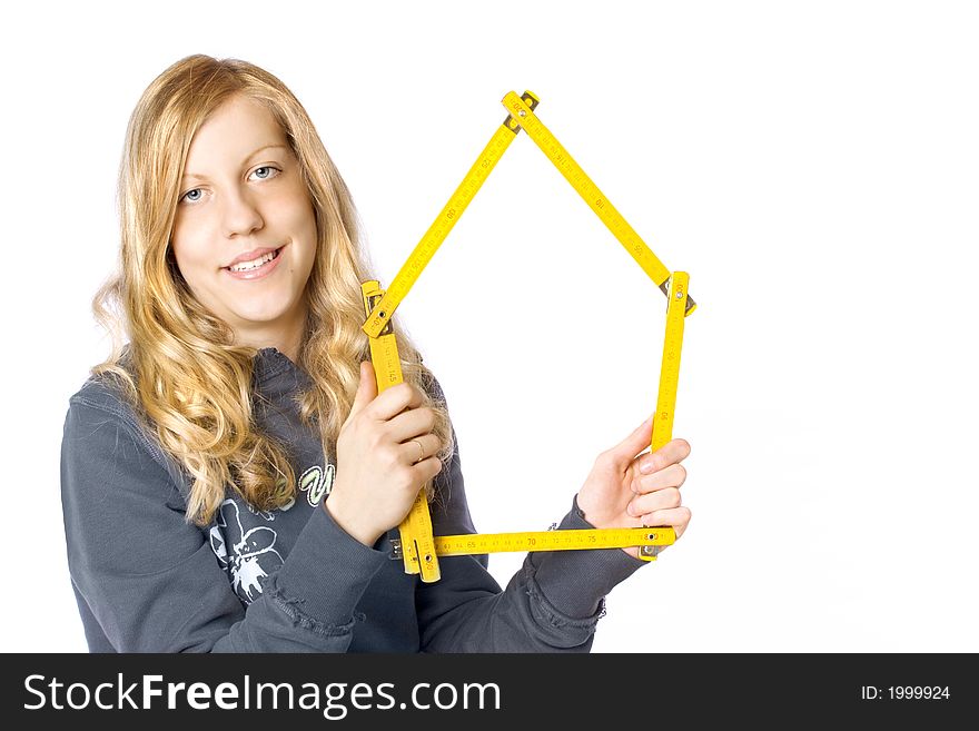 Young girl holding a metre measure (notice a house shape) near her face. A concept of a new house or a renovation. Young girl holding a metre measure (notice a house shape) near her face. A concept of a new house or a renovation.