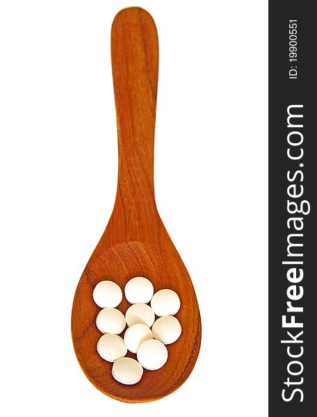 Wooden spoon with pills isolated on white background