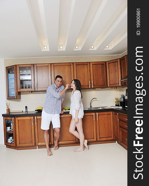 Happy young couple have fun in modern wooden kitchen indoor while preparing fresh food. Happy young couple have fun in modern wooden kitchen indoor while preparing fresh food