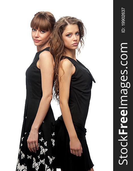 Two young women in dark dresses on the isolated background