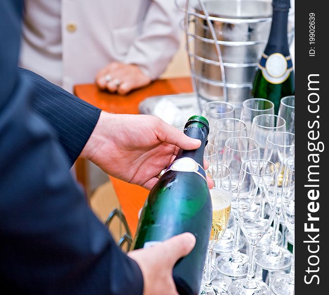 Man in suite pouring champagne to glasses