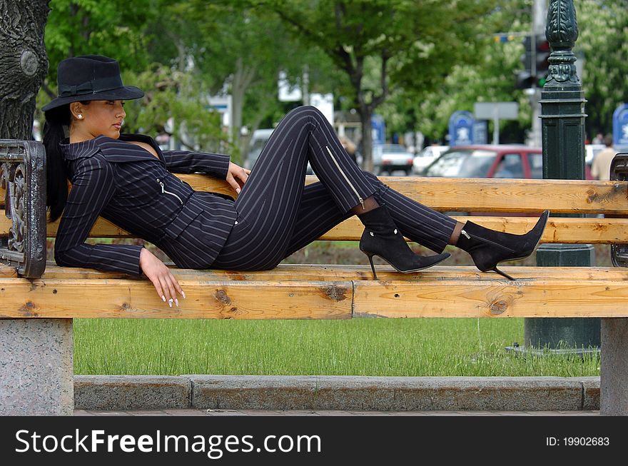 Woman in an elegant suit sitting on a bench in the park