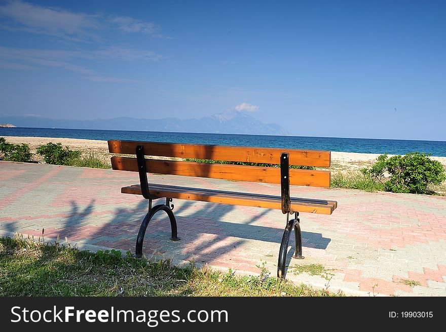 Wooden bench on the promenade at the seafront withg sky without clouds