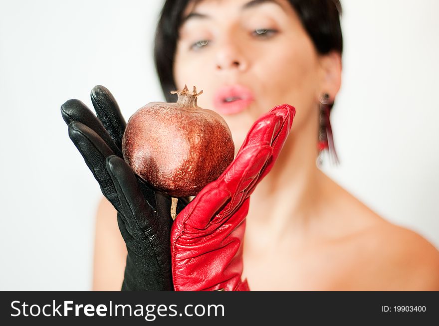 A girl with red and black gloves taken a pomegranate. A girl with red and black gloves taken a pomegranate