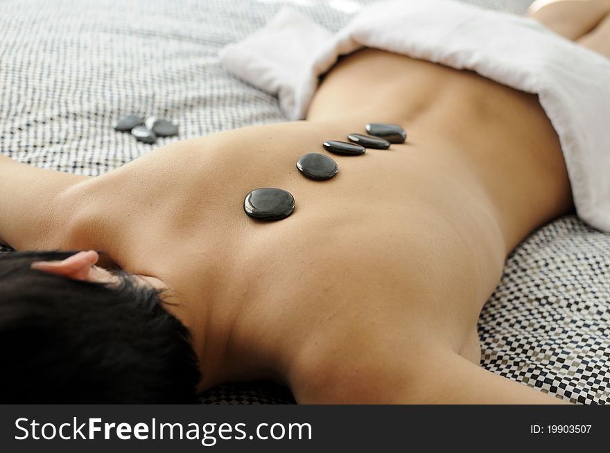 Woman getting hot stone massage with black pebbles