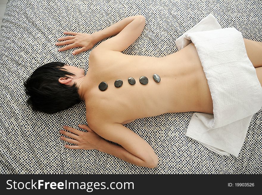 Woman getting hot stone massage with black pebbles