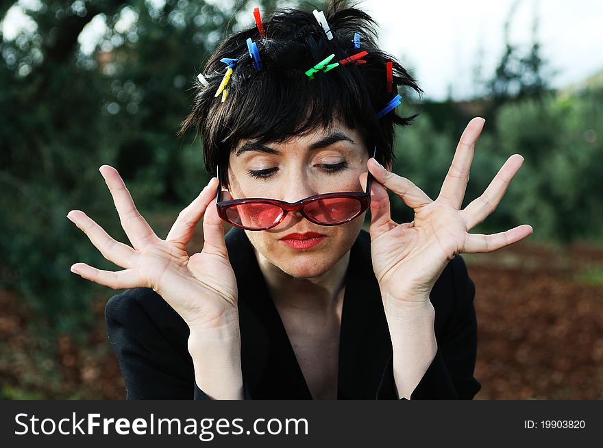 Funny picture of a girl with her hair adorned with clothespins, wearing cheerful sunglasses subject with her hands. Funny picture of a girl with her hair adorned with clothespins, wearing cheerful sunglasses subject with her hands.