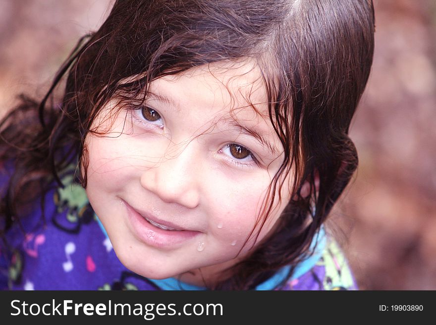 Portrait of a pretty little girl with wet hair smiling up