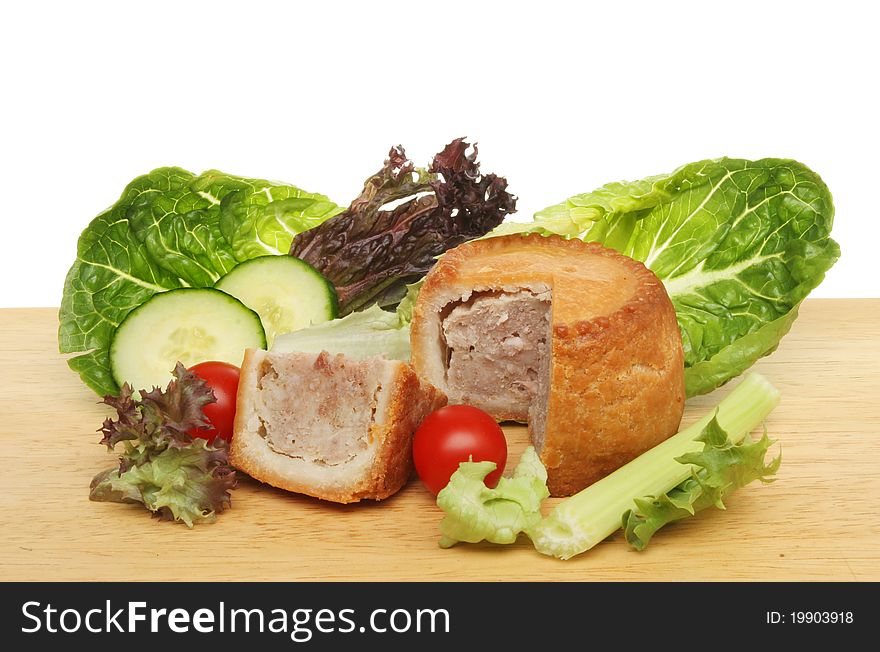 Pork pie and salad on a wooden food preparation board