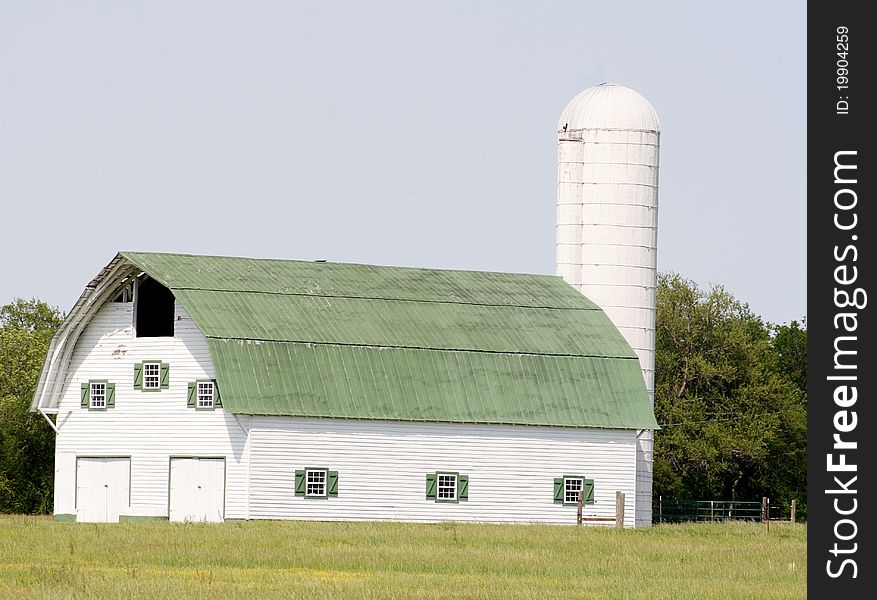 Beautiful white barn with green roof in the summer