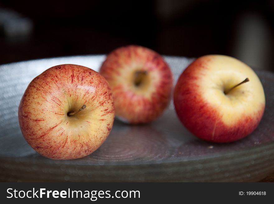 Three apples on a glass plate