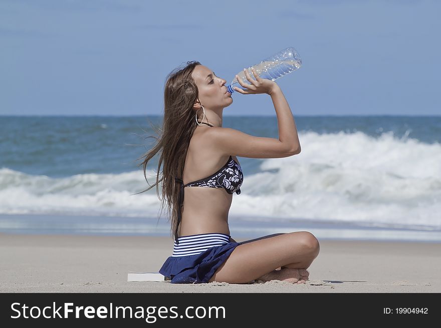 Woman drinking water in the beach