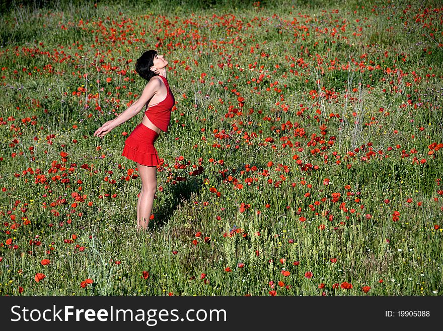 A girl dressed in red, smelling a field of poppies, with feeling joy, happiness and freedom. A girl dressed in red, smelling a field of poppies, with feeling joy, happiness and freedom