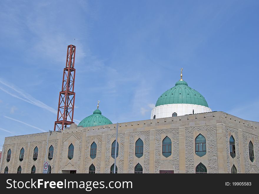 The Green Domes and Minaret of a modern Mosque in a mill town in West Yorkshire under a blue sky. The Green Domes and Minaret of a modern Mosque in a mill town in West Yorkshire under a blue sky