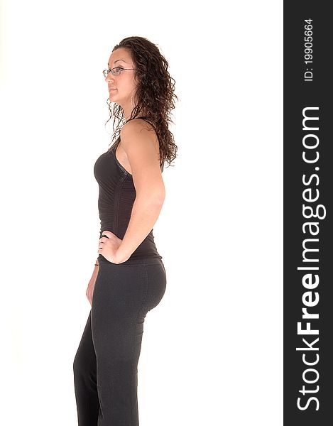 A young pretty woman standing in the studio in profile, showing her nice figure, with glasses and curly hair, for white background. A young pretty woman standing in the studio in profile, showing her nice figure, with glasses and curly hair, for white background.