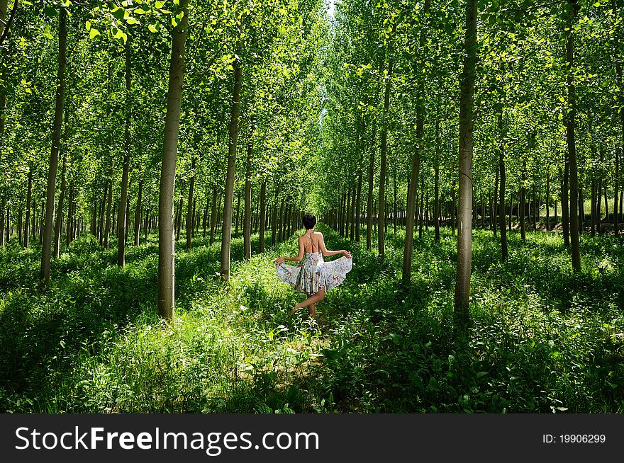 A woman dancing between trees wearing a dress. A woman dancing between trees wearing a dress