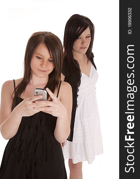 A teen girl looking over a shoulder while her friend is texting and not liking what her friend is texting. A teen girl looking over a shoulder while her friend is texting and not liking what her friend is texting.