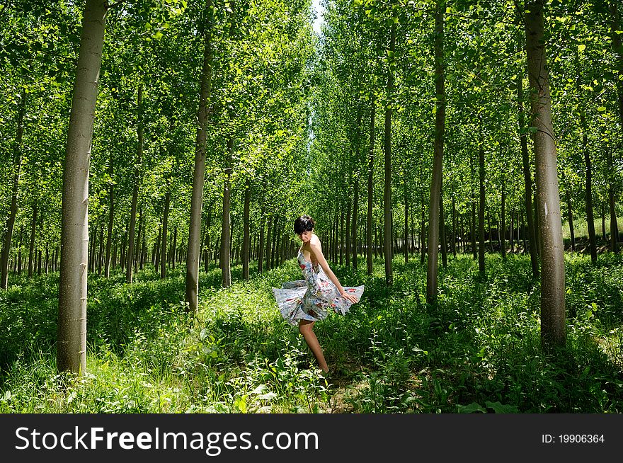 A woman dancing between trees wearing a dress. A woman dancing between trees wearing a dress