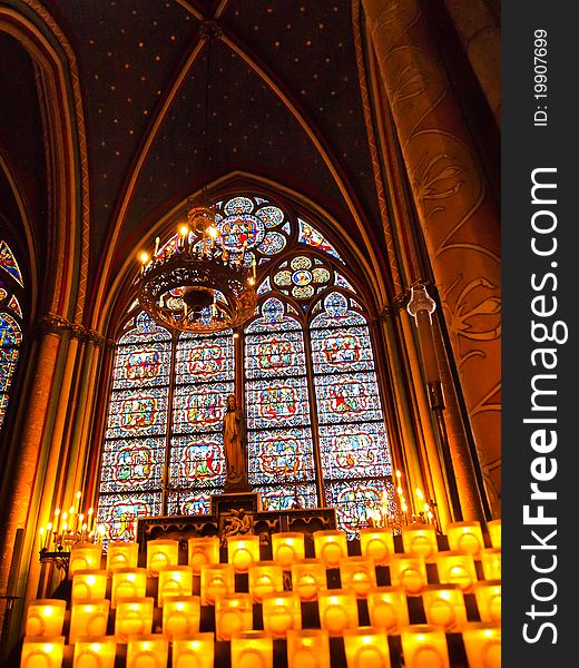 Candles in front of a stained window at Notre Dame Cathedral in Paris, France. Candles in front of a stained window at Notre Dame Cathedral in Paris, France.