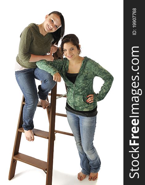 Portrait of two beautiful young teens in casual clothes posed with an old ladder. Portrait of two beautiful young teens in casual clothes posed with an old ladder.