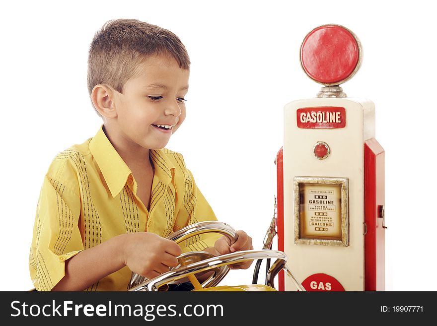 An adorable preschooler happily driving his car by an old-time gas pump. Isolated on white. An adorable preschooler happily driving his car by an old-time gas pump. Isolated on white.