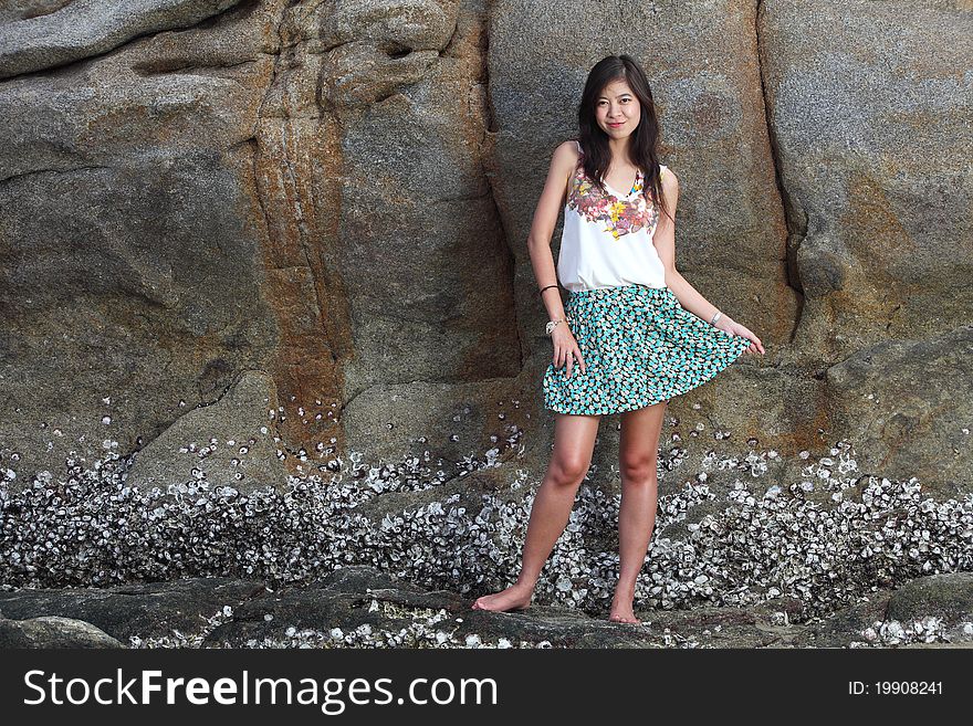 Beautiful young woman posing on stones near sea